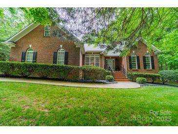 Charming brick home featuring manicured landscaping, a walkway leading to the front door, and complemented by lush greenery at 4033 Weddington Manor Ct, Matthews, NC 28104