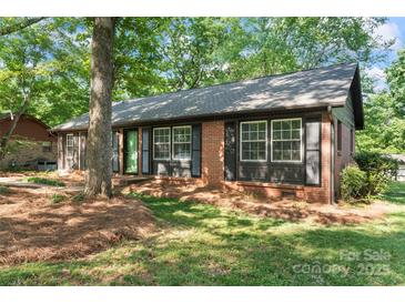 Charming brick home with a green front door and black shutters surrounded by mature trees at 606 Deer Creek Dr, Matthews, NC 28105