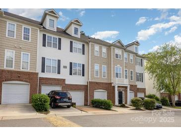 View of townhome exterior with brick accents, multiple floors, and garages at 6912 Park Place Dr, Charlotte, NC 28262