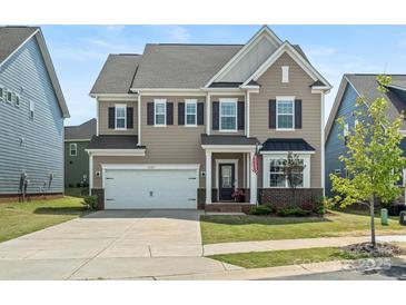 Charming two-story home features a two-car garage, manicured lawn, and an inviting front porch at 1005 Cheviot Ct, Waxhaw, NC 28173