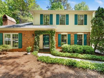 Charming two-story brick home featuring green shutters, a lush ivy-covered entrance, and manicured landscaping at 1325 Rock Point Rd, Charlotte, NC 28270