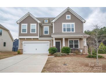 Charming two-story home featuring a two-car garage and a welcoming front porch with stone accents at 150 Falls Cove Dr, Troutman, NC 28166
