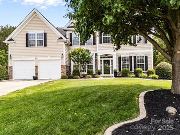 Charming two-story home with a manicured lawn, mature tree, and two-car garage at 1900 Birchbrook Ct, Harrisburg, NC 28075