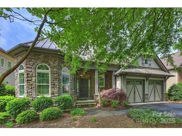 Stunning stone home featuring an arched entryway, manicured landscaping, and attached two car garage at 4122 Banfield Pl, Charlotte, NC 28226
