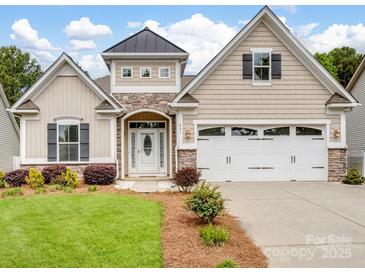 Charming home featuring stone accents, a two-car garage, manicured lawn and a covered front porch at 581 Harrison Nw Dr, Concord, NC 28027