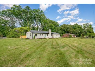 Charming single-story home featuring freshly cut grass and a painted brick facade and a bright teal front door at 6301 Vernedale Rd, Charlotte, NC 28212