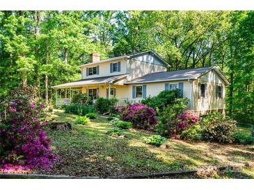 Charming two-story home featuring a covered porch and surrounded by lush landscaping with colorful flowers and mature trees at 6766 Little Mountain Rd, Sherrills Ford, NC 28673