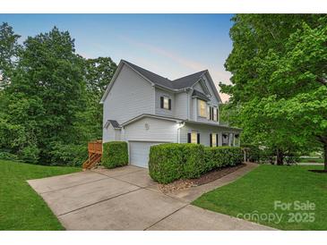 Charming home with white siding, black shutters, a well-manicured lawn, and mature trees at 7049 Sedgebrook W Dr, Stanley, NC 28164
