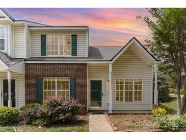 Charming townhome featuring a brick accent wall, green shutters, and well-maintained landscaping at 7718 Petrea Ln, Charlotte, NC 28227