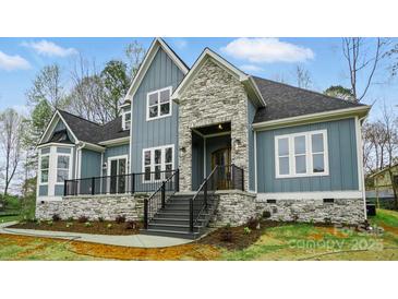 Beautiful home with blue siding, stone accents, black railings, and professional landscaping at 149 Shady Cove Rd, Troutman, NC 28166