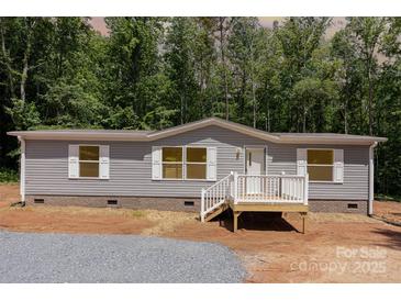 Charming single-story home with gray siding, white trim, and a small front porch nestled among lush green trees at 1785 Doe Ct, Iron Station, NC 28080