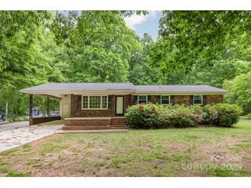 Charming brick home with mature trees, covered carport, and blooming bushes in the front yard at 1874 Sunny Ln, Lancaster, SC 29720