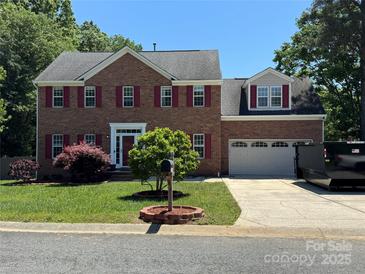 Charming two-story brick home featuring red shutters, a well-manicured lawn, and an attached two-car garage at 3602 Brookstone Trl, Indian Trail, NC 28079