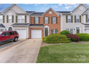 Charming townhome featuring a brick facade, attached garage, well-maintained lawn, and delightful landscaping at 4208 Carl Parmer Dr, Harrisburg, NC 28075