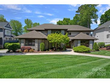 Stunning exterior of stone home with manicured lawn and lush landscaping at 19501 River Falls Dr, Davidson, NC 28036