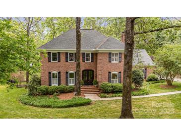 Charming two-story brick home with black shutters, manicured lawn and mature trees at 2600 Oakmeade Dr, Charlotte, NC 28270