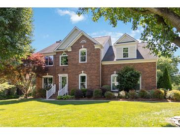Beautiful two-story brick home featuring a well-maintained lawn and mature landscaping at 7700 Ninth Fairway Ln, Mint Hill, NC 28227