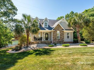 Charming home featuring stone accents, a covered porch, and a beautifully landscaped front yard with mature palm trees at 125 Mariner Pointe Ln, Mooresville, NC 28117