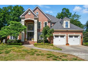Stately brick home featuring an arched entry, two-car garage, and manicured lawn at 16216 Woolwine Rd, Charlotte, NC 28278