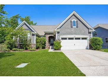 Charming home with stone accents, well-manicured lawn, and a two-car garage with a blue sky in the background at 16427 Cozy Cove Rd, Charlotte, NC 28278