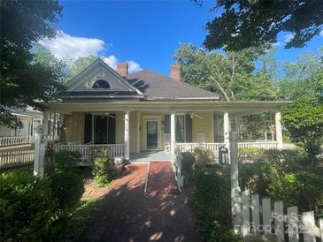 Charming yellow two-story home with a brick walkway and covered porch, showcasing curb appeal and a welcoming entrance at 500 W Council St, Salisbury, NC 28144