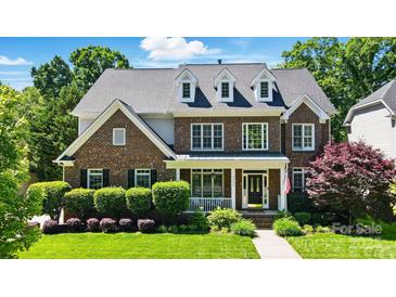 Charming brick two-story home featuring a well-manicured lawn and a welcoming front porch at 7722 Garnkirk Dr, Huntersville, NC 28078