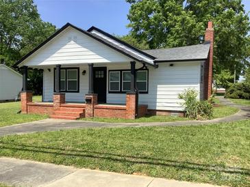 Charming single-story home features a brick chimney and inviting front porch with brick columns at 913 Winchester Ave, Monroe, NC 28110