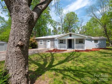 Charming one-story home featuring a covered front porch and a well-maintained lawn with mature trees at 105 Strickland Ln, Bessemer City, NC 28016
