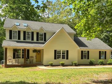 Charming two-story home with light yellow siding, black shutters, and a welcoming front porch with rocking chairs at 1338 Pell Dr, Lincolnton, NC 28092