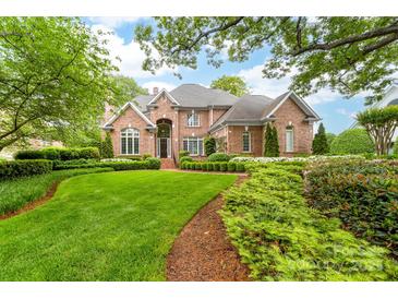 Stunning two-story brick home featuring a meticulously landscaped front yard with lush green grass and manicured bushes at 18920 Peninsula Club Dr, Cornelius, NC 28031