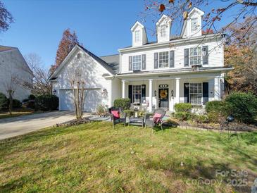 Charming two-story home with a well-manicured lawn, seating, and a welcoming front porch at 5076 Timber Falls Dr, Indian Land, SC 29707