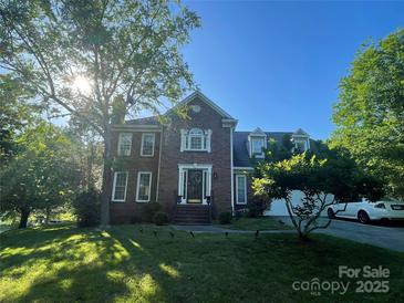 Beautiful two-story brick home featuring a landscaped front yard and lovely architectural details under a bright blue sky at 944 Evian Ln, Matthews, NC 28015