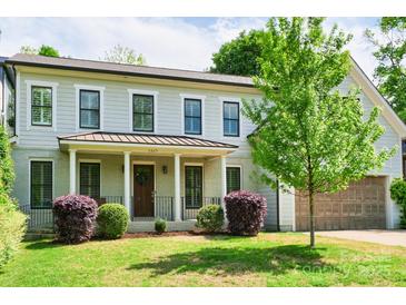 Charming two-story home featuring light gray siding, black trim, a welcoming front porch and well manicured landscaping at 1517 Waverly Ave, Charlotte, NC 28203