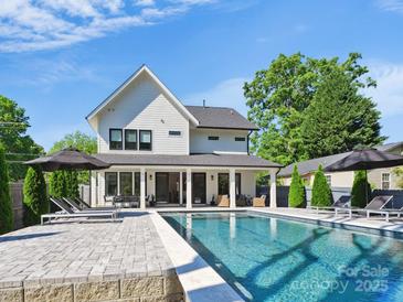 Stunning backyard featuring a sparkling pool, lounge chairs, and a covered patio perfect for outdoor entertaining at 1009 Belmont Ave, Charlotte, NC 28205