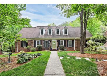 Charming brick home featuring dormer windows, a well-manicured lawn, and a welcoming walkway at 10209 Thomas Payne Cir, Charlotte, NC 28277