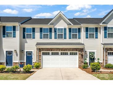 Charming townhome with a two-car garage, blue shutters, and a beautifully landscaped front yard at 10436 Dalton Woods Nw Ct, Huntersville, NC 28078