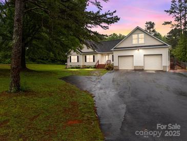 Charming home with an attached two-car garage and spacious front yard at dusk at 140 Ribbon Cir, Lincolnton, NC 28092