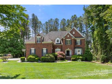 Charming two-story brick home featuring a well-manicured lawn, mature trees, and classic architectural details at 221 Silvercliff Dr, Mount Holly, NC 28120
