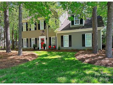 Charming two-story home featuring a manicured lawn, red front door, and beautiful landscaping at 2600 Kirkholm Dr, Matthews, NC 28105