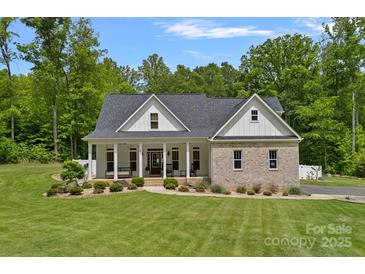 Charming brick home featuring a covered front porch and lush green lawn with mature trees at 270 Worthington Dr, Mt Ulla, NC 28125