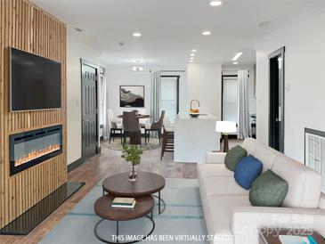 Bright living room with modern fireplace, open floor plan, dining area, and kitchen with large island at 3150 Driftwood Dr # B, Charlotte, NC 28205