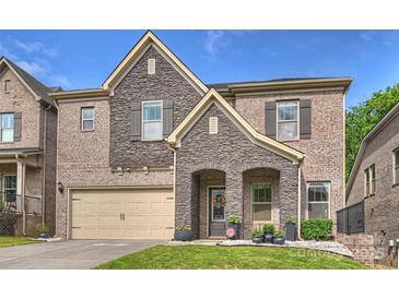 Charming two-story brick home with a stone facade, attached garage, and well-manicured lawn at 6618 Vizcaya Ct, Charlotte, NC 28226