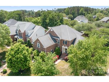 Beautiful brick home showcasing lush landscaping, mature trees, and a well-maintained lawn at 7525 Blackgum Falls Ct, Huntersville, NC 28078