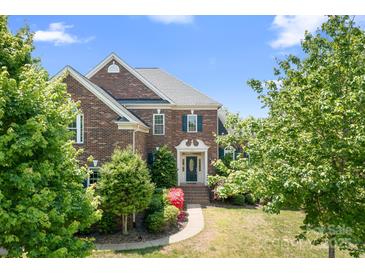 Charming brick home featuring lush landscaping, a welcoming entrance, and mature trees on a sunny day at 7525 Blackgum Falls Ct, Huntersville, NC 28078