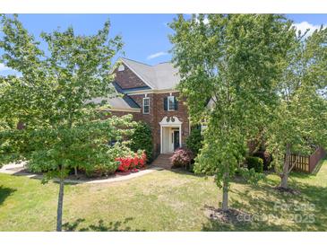 Beautiful home with a manicured lawn, mature trees, brick exterior, and inviting front entrance on a sunny day at 7525 Blackgum Falls Ct, Huntersville, NC 28078