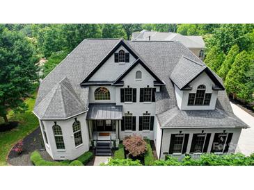 Stunning two-story home featuring a gray roof, white brick, black shutters and meticulously manicured landscaping at 8707 Fairview Rd, Charlotte, NC 28226