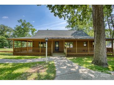 Charming log cabin with a covered porch, mature trees, and a well-manicured lawn at 993 Jackson Rd, Fort Lawn, SC 29714