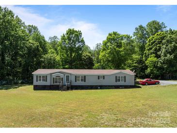 Charming single-story home on a lush green lawn with mature trees in the background at 145 Mccreek Dr, China Grove, NC 28023