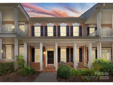 Charming two-story brick home with a welcoming front porch and beautiful landscaping at sunset at 155 Harper Lee St, Davidson, NC 28036