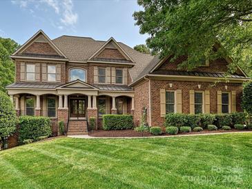 Elegant brick home featuring manicured lawn, covered porch with stately columns, and traditional shuttered windows at 16319 Ashlyn Chase Ct, Charlotte, NC 28277